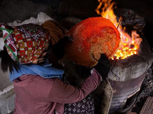 Để có những chiếc bánh đa dừa nướng thơm ngon, người thợ làng Thổ Hà phải ngồi bên bếp than hồng rực lửa hàng giờ đồng hồ, nhanh tay xoay đều để bánh chín vàng ruộm, giòn tan mà không bị cháy. (Ảnh: Hà Anh/TTXVN phát)