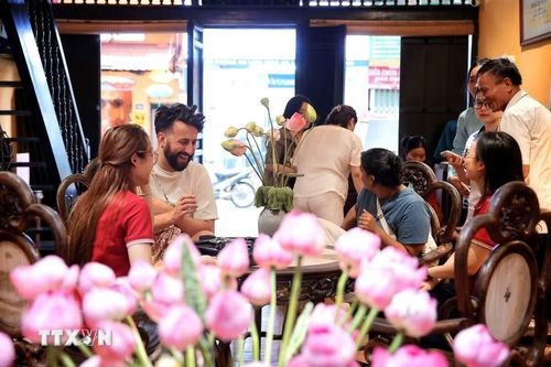Du khách nước ngoài được giới thiệu về nghệ thuật thưởng trà sen trong không gian di sản giữa lòng phố cổ Hà Nội. (Ảnh: Phạm Tuấn Anh/TTXVN)