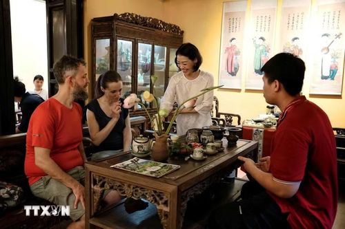 Du khách quốc tế trải nghiệm không gian thưởng trà và tìm hiểu nghệ thuật trà sen truyền thống tại Ngôi nhà Di sản 87 Mã Mây, Hà Nội. (Ảnh: Phạm Tuấn Anh/TTXVN)
