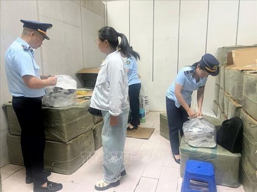 Cán bộ Đội Quản lý thị trường số 1 kiểm tra các bao hàng chứa giày thể thao giả mạo nhãn hiệu Nike được tập kết trôi nổi tại một ki-ốt thuộc chợ Trung tâm, phường Móng Cái 1. Ảnh: TTXVN phát
