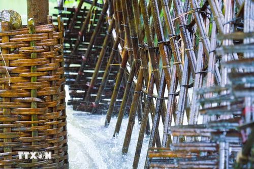 Sức bền, độ chắc chắn của bánh quay cọn nước có được nhờ hàng trăm cọc nứa, tre già đan chéo, liên kết với nhau với những nút buộc bằng dây lạt, dây mây tại điểm giao nhau. (Ảnh: Xuân Tiến/TTXVN)