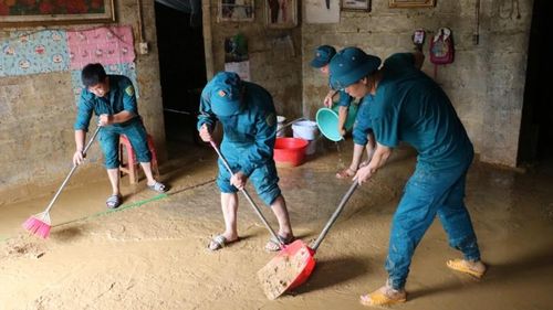 Lực lượng dân quân hỗ trợ người dân dọn dẹp bùn đất, vận chuyển đồ đạc sau lũ.