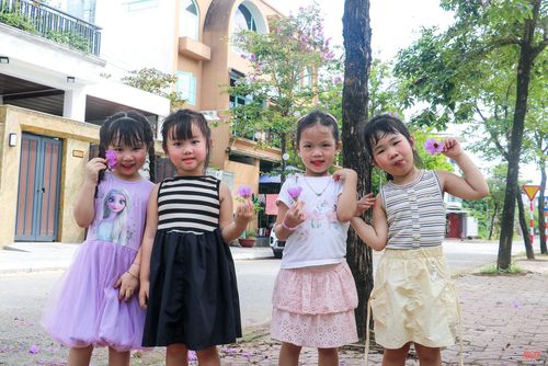 Các em bé thích thú khi được chụp ảnh với hoa bằng lăng.