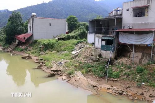 Bờ suối Ngòi Hút bị sạt lở, xói mòn sâu từ 6-8m vào nhà ở các hộ dân. (Ảnh: Đinh Thùy/TTXVN)