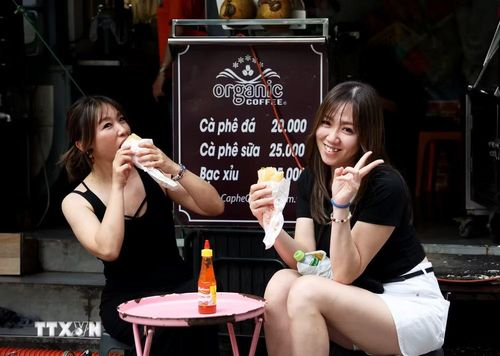Khách du lịch Nhật Bản thưởng thức bánh mì ở quán cà phê vỉa hè đường Pasteur, phường Bến Thành, Thành phố Hồ Chí Minh. (Ảnh: Hồng Đạt/TTXVN)