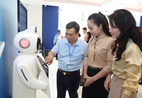 Cán bộ Trung tâm Dịch vụ hành chính công thành phố Hà Nội hướng dẫn người dân sử dụng robot ảo để tư vấn các thủ tục hành chính. Ảnh: Nhật Nam