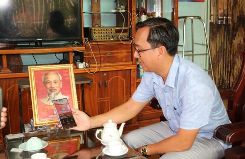 Đảng viên quét mã QR Code in dưới ảnh Bác Hồ để tìm hiểu những thông tin, câu chuyện kể về Bác. Ảnh: Nhựt An - TTXVN