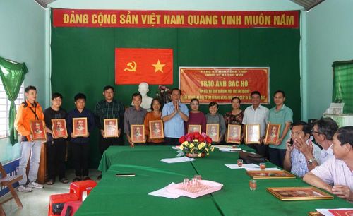 Đồng chí Lê Minh Trung, Bí thư Đảng ủy xã Phú Hựu trao tặng ảnh Bác Hồ (gắn mã QR Code liên kết đến kho dữ liệu số, cung cấp thông tin và những chuyện kể về Bác) cho đảng viên Chi bộ ấp An Hòa. Ảnh: Nhựt An - TTXVN