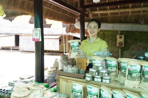 Chị Nguyễn Thị Tuyết bán các sản phẩm đặc sản quê Bác tại không gian nhà cụ cố Điền được phục dựng lại. Ảnh: Hồ Lài