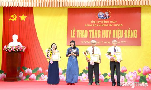 Đồng chí Lê Thị Bé Phượng, Bí thư Đảng ủy, Chủ tịch HĐND phường Mỹ Phong, trao Huy hiệu Đảng và hoa, Khánh vàng lưu niệm cho các đảng viên.