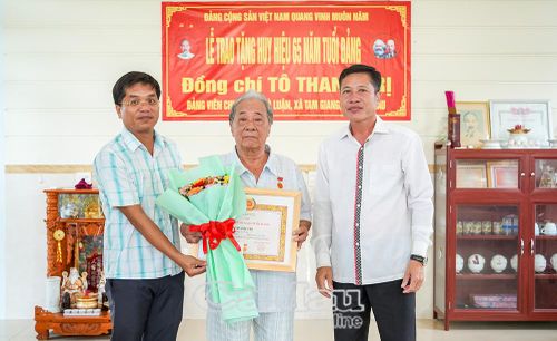 Trưởng Ban Nội chính Tỉnh ủy Cà Mau Trần Hữu Phước (bìa phải) và đồng chí Lâm Anh Đức, Bí thư Đảng ủy, Chủ tịch HĐND xã Tam Giang trao Huy hiệu 65 năm tuổi Đảng cho đồng chí Tô Thanh Trị.