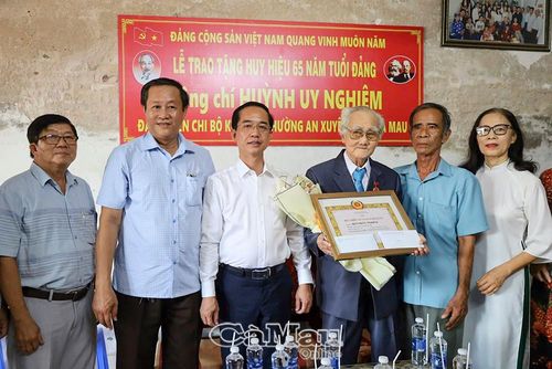  Phó Bí thư Tỉnh ủy, Chủ tịch Ủy ban MTTQ Việt Nam tỉnh Cà Mau Hồ Thanh Thủy vchụp ảnh lưu niệm cùng đảng viên Huỳnh Uy Nghiêm và gia đình.