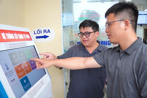  Bạn Tạ Minh Chánh Đức (trái) hướng dẫn các thao tác lấy số thứ tự trên app “eGov An Lạc - Ứng dụng lấy số thứ tự trực tuyến” cho người dân. ẢNH: QUANG HUY 