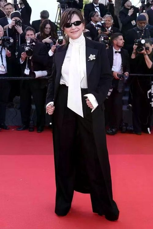 Juliette Binoche khẳng định sức hút bằng bộ suit gồm áo khoác dài và quần palazzo rộng. Điểm nhấn nằm ở chiếc ghim cài áo đồng điệu với hàng cúc trắng.