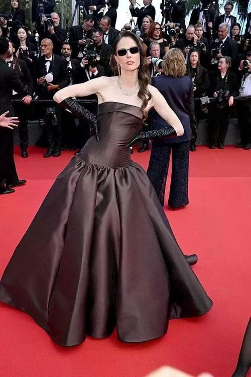 Coco Rocha cũng gây chú ý với bộ váy màu chocolate thiết kế cầu kỳ, kết hợp chân váy satin bóng, găng tay da đen, trang sức kim cương và kính râm vuông bản lớn.