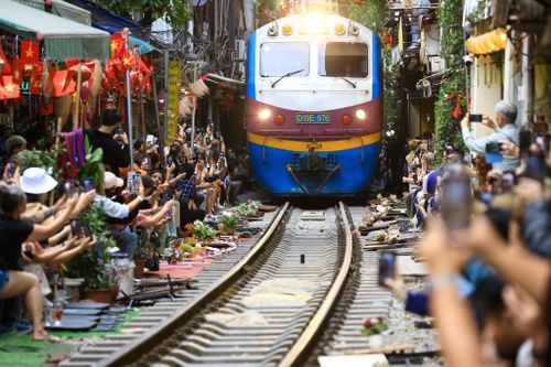  Du khách ngồi sát đường ray, đồng loạt quay phim, chụp ảnh khi đoàn tàu đi qua. Ảnh: Trần Hiền. 