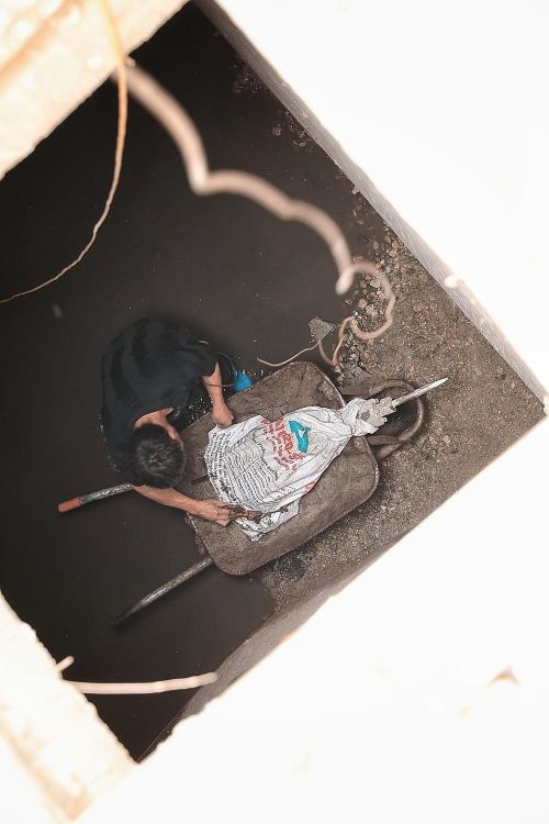 Công nhân chuyển vật dụng và dọn dẹp dưới hố ga ngầm tại khu vực thi công trước chợ Hàng Da. Ảnh: Phạm Tuấn Anh - TTXVN