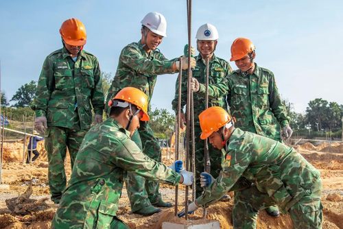 Thiếu tá Đinh Văn Tháo (thứ 3 từ phải sang) đang cùng anh em thi công phần móng nhà. Ảnh: Lê Văn Chương