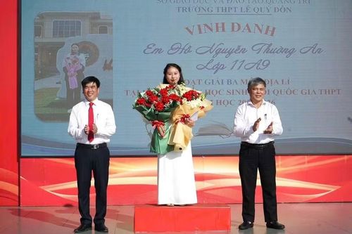 Ông Nguyễn Phú Hữu, Hiệu trưởng Trường THPT Lê Quý Đôn (bên trái) trao thưởng cho em Hồ Nguyễn Thường An vì thành tích học tập xuất sắc.