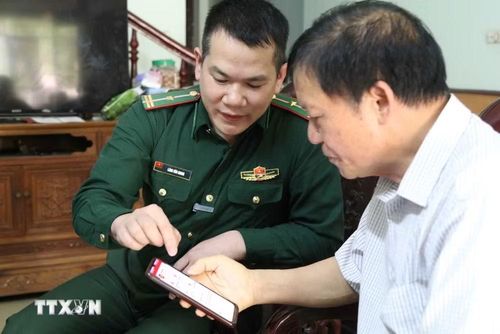 Cán bộ Đồn Biên phòng cửa khẩu Chi Ma, tỉnh Lạng Sơn, hướng dẫn người dân xã Mẫu Sơn sử dụng các ứng dụng số trên điện thoại thông minh. (Ảnh: Quang Duy/TTXVN)