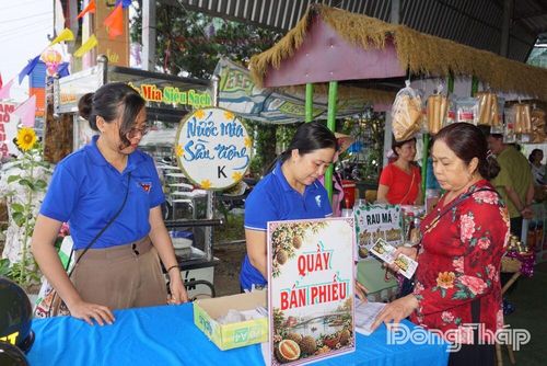 Người dân và du khách phấn khởi mua phiếu trải nghiệm các món ăn độc lạ tại quầy bán phiếu ẩm thực của phiên chợ.