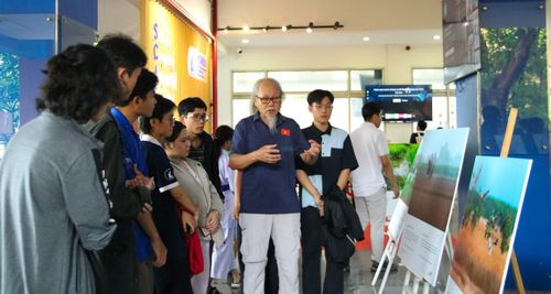 Nhiếp ảnh gia Nguyễn Trường Sinh tận tình giải đáp thắc mắc về đời sống của sếu đầu đỏ ở không gian triển lãm. Ảnh: Huyền Trang