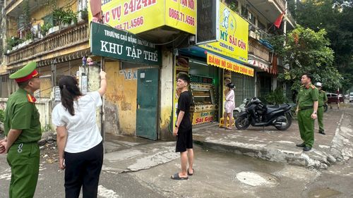 Cán bộ xã Thường Tín hướng dẫn chủ cơ sở kinh doanh tại khu vực tập thể Trường Cao đẳng Truyền hình ở ven đường 427 tháo dỡ biển quảng cáo không bảo đảm quy định. Ảnh: PV