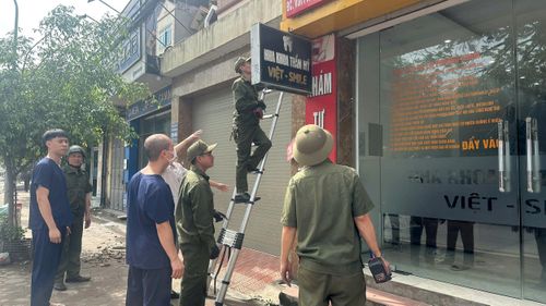 Công an xã Thường Tín vận động các hộ kinh doanh, yêu cầu chấp hành các quy định tháo dỡ biển quảng cáo không phù hợp gây mất mỹ quan đô thị. Ảnh: PV