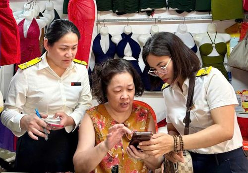 Cán bộ Thuế hướng dẫn hộ kinh doanh. Ảnh: PV