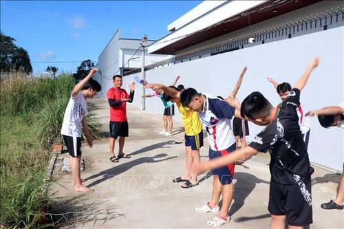 Giáo viên hướng dẫn học sinh thực hiện các bài tập khởi động và kéo giãn cơ trên bờ trước khi xuống nước luyện tập.