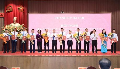 Bí thư Thành ủy Hà Nội Trần Đức Thắng và Thường trực Thành ủy trao quyết định của Ban Thường vụ Thành ủy về công tác cán bộ và tặng hoa chúc mừng các cán bộ nhận nhiệm vụ mới (Ảnh: Quang Thái).