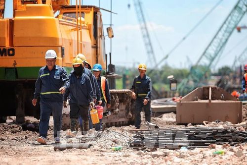 Nhóm công nhân tranh thủ di chuyển, nghỉ ngắn giữa ca làm việc ngoài trời tại công trường xây dựng. Ảnh: Phạm Tuấn Anh - TTXVN