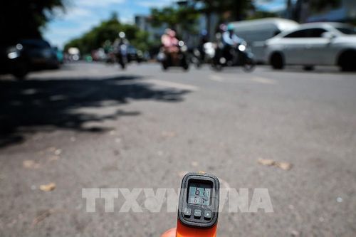 Thiết bị đo nhiệt cho thấy nhiệt độ bề mặt mặt đường ngoài trời lên tới hơn 61 độ C vào thời điểm giữa trưa ngày 25/5. Ảnh: Phạm Tuấn Anh - TTXVN