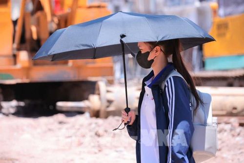 Người dân tìm mọi cách chống nắng khi phải di chuyển trên đường. Ảnh: Hoàng Hiếu - TTXVN