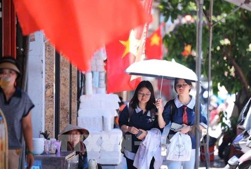 Người dân tìm mọi cách chống nắng khi phải di chuyển trên đường. Ảnh: Hoàng Hiếu - TTXVN