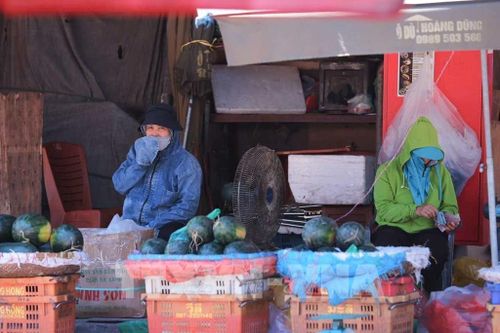 Thời tiết ngoài trời tăng cao khiến các tiểu thương chợ Long Biên vẫn phải mặc đồ chống nắng để tránh mất nhiệt cơ thể. Ảnh: Hoàng Hiếu - TTXVN