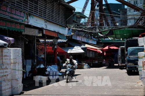 Người lao động di chuyển qua khu vực chợ đầu mối trong khung giờ nắng gắt, khi nhiều tuyến phố gần như vắng bóng người đi bộ. Ảnh: Phạm Tuấn Anh - TTXVN