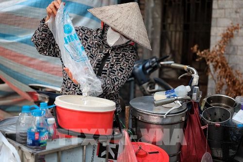 Một người bán hàng rong giữ đồ uống mát lạnh phục vụ khách giữa đợt nắng nóng đầu hè. Ảnh: Phạm Tuấn Anh - TTXVN