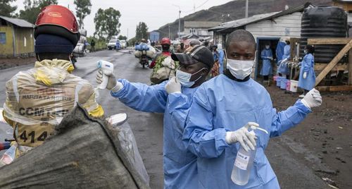 Các nhân viên y tế được điều động để ứng phó với dịch Ebola đang kiểm tra thân nhiệt và cung cấp nước rửa tay sát khuẩn cho những người đi xe máy qua trạm kiểm soát Kanyaruchinya, phía bắc Goma - Congo. Ảnh: LTD.