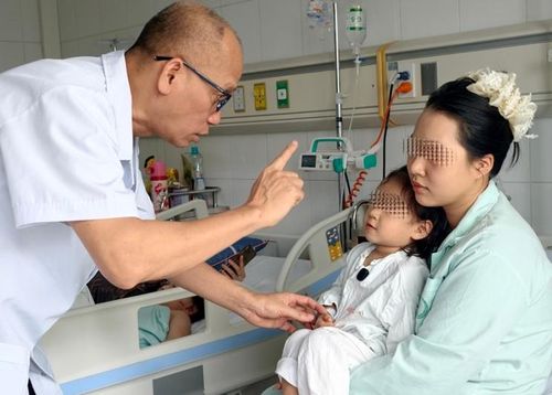 PGS.TS Nguyễn Hồng Hà thăm khám cho bệnh nhi sau ca phẫu thuật.