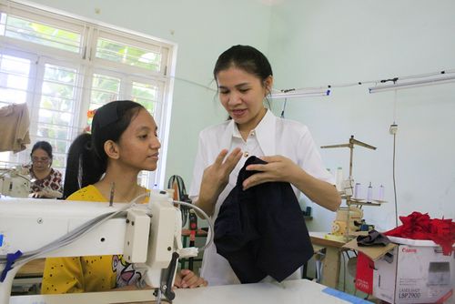 Cô giáo trợ giảng Nguyễn Thị Kim Ngân (Trung tâm Nuôi dạy trẻ khuyết tật Võ Hồng Sơn, xã Nghĩa Hành, tỉnh Quảng Ngãi) hướng dẫn học sinh cách may quần áo. ẢNH: NGUYỄN TRANG