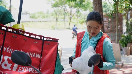 Nữ shipper cố gắng hoàn thành công việc trong thời tiết bất lợi.