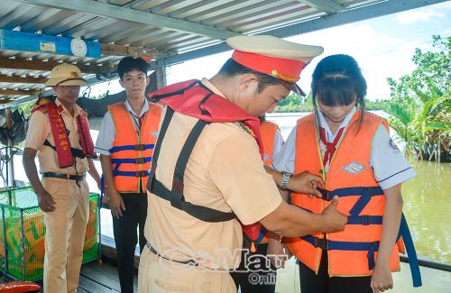 Cán bộ Trạm Cảnh sát đường thuỷ Thới Bình hướng dẫn học sinh mặc áo phao khi qua đò, phà.