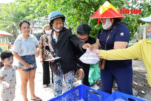 Bà Tô Thị Thúy (bệnh nhân chạy thận), cầm xấp vé số đang đi bán đến nhận suất cơm từ nhóm thiện nguyện.