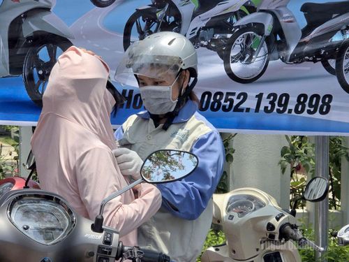 Phụ huynh mặc áo chống nắng cho con đến điểm thi.