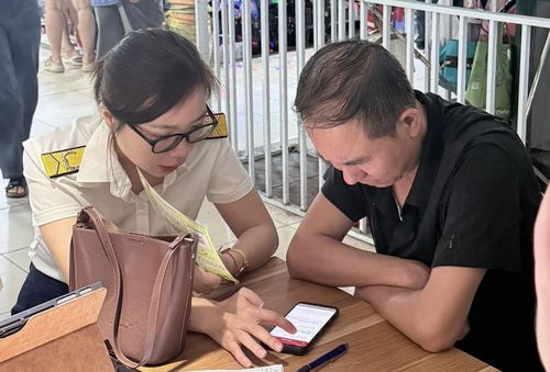 Công chức thuế hỗ trợ hộ kinh doanh nộp thuế trên ứng dụng eTax Mobile. Ảnh: TN