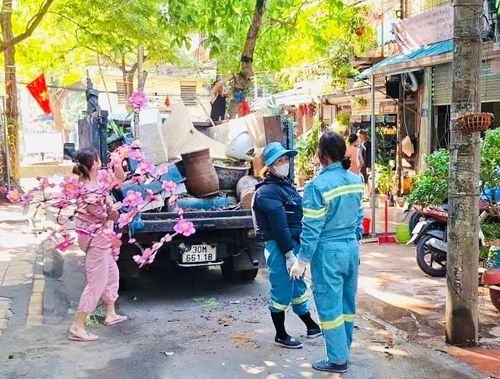 Công nhân môi trường thực hiện thu gom các chậu cây, vật dụng cản trở lối đi của người dân. Ảnh: PV