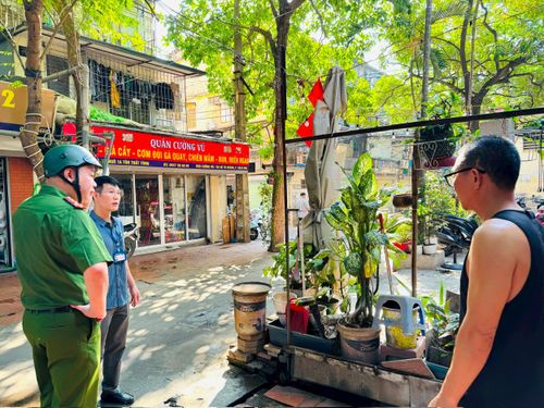 Lực lượng chức năng phường Kim Liên nhắc nhở, tuyên truyền việc dọn dẹp chậu cây, vật dụng cản trở lối đi của người dân. Ảnh: PV