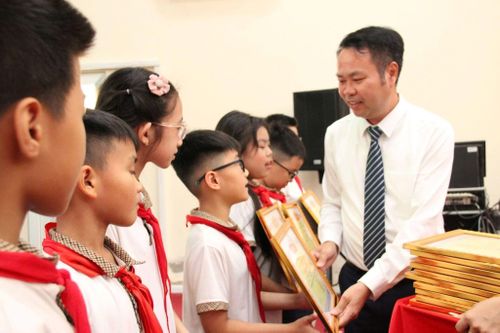 Chủ tịch UBND xã Hòa Lạc Đào Xuân Ban trao thưởng cho các em học sinh giỏi xuất sắc. Ảnh: PV