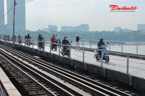 Nhiều người dân và du khách thong thả đi bộ, dừng chân chụp ảnh trên cầu Long Biên, tận hưởng không gian hoài cổ và ngắm nhìn khung cảnh sông Hồng sau ngày cây cầu chính thức thông xe trở lại.